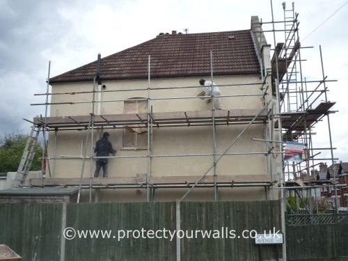 A house covered in scaffolding, in the process of being rendered.