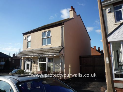 Freshly rendered beige house, three-quarter view.