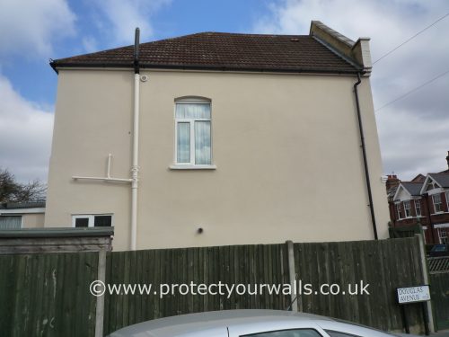 A house with new render and tan paint, side view.